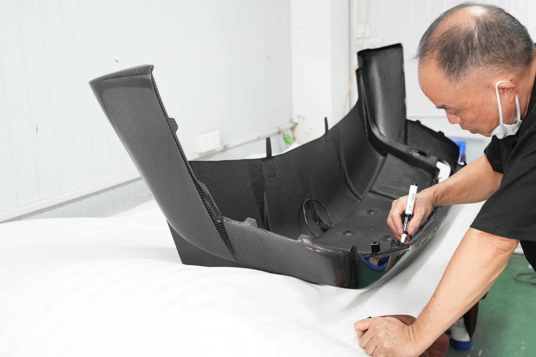 A CMST technician trial-fitting a part against the actual car during development