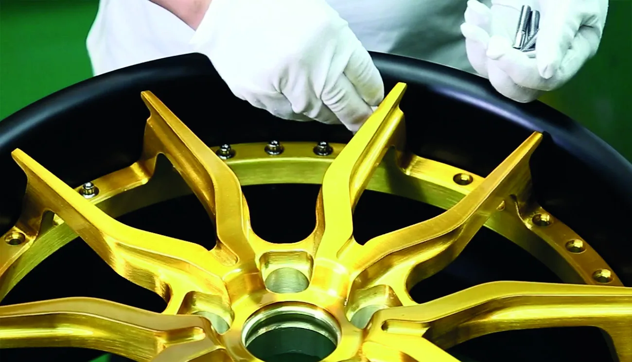 A two-piece forged wheel face being bolted into its barrel